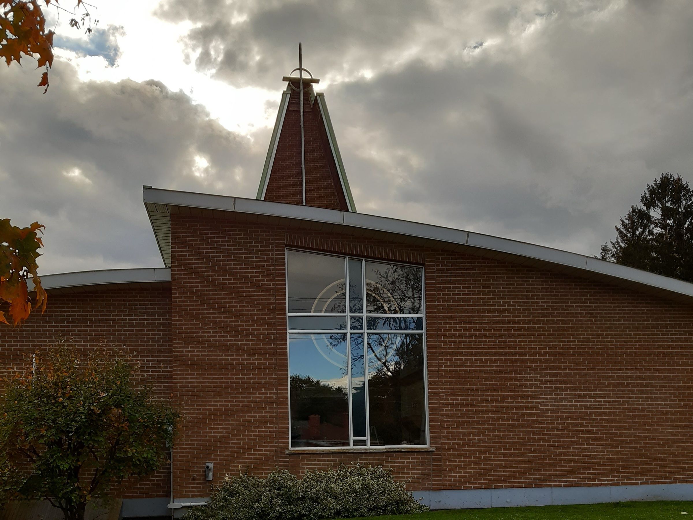 The brick church on Victoria Road North where Living Word meets, with a tall cross-framed window and a pointed spire